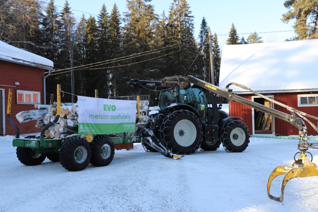 Metsäkone. Peräkärryssä kankainen kyltti "Evo".