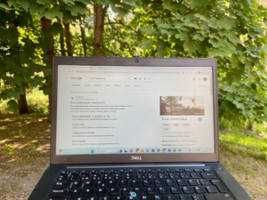 Kannettava tietokone auki. Taustalla metsä. Google-hakukoneen sivu auki.