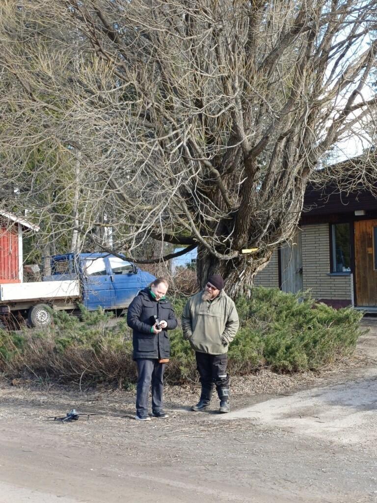 kaksi henkilöä ulkona ison puun edessä. 