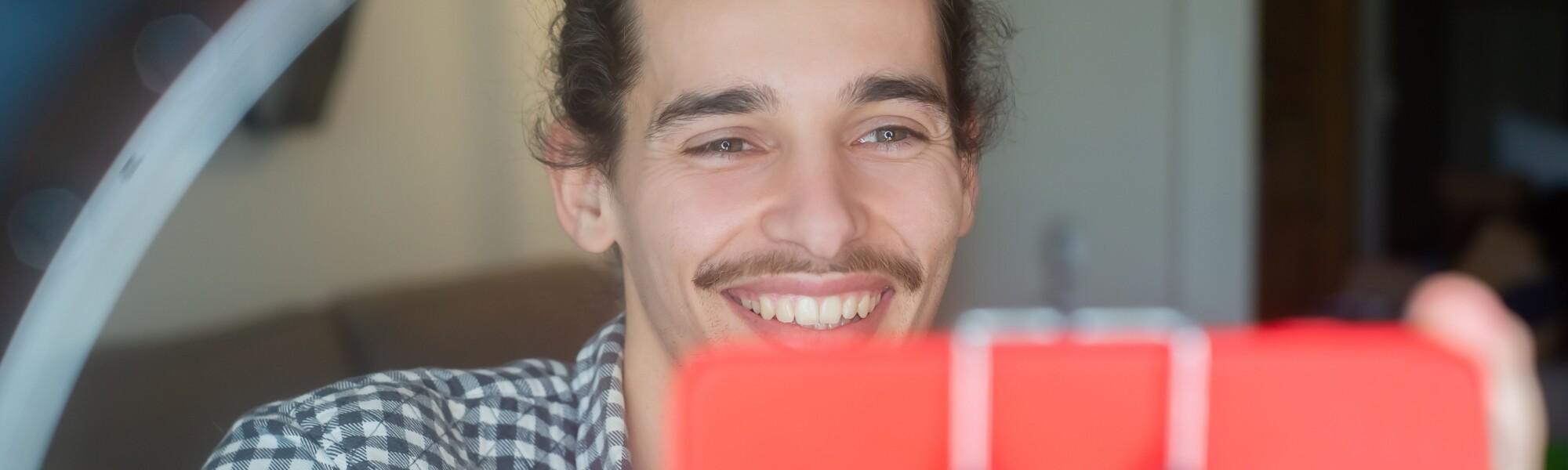 a man holding a smartphone. the man is smiling.